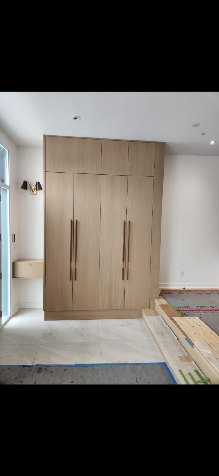Unité de rangement pleine hauteur en bois clair avec banc intégré dans une entrée