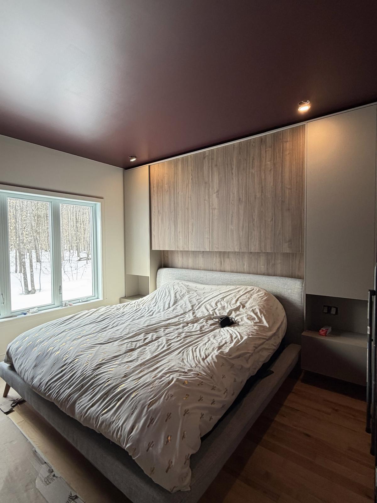 Chambre avec rangement intégré sur mesure autour du lit, ponts d'armoires en bois et tables de nuit suspendues