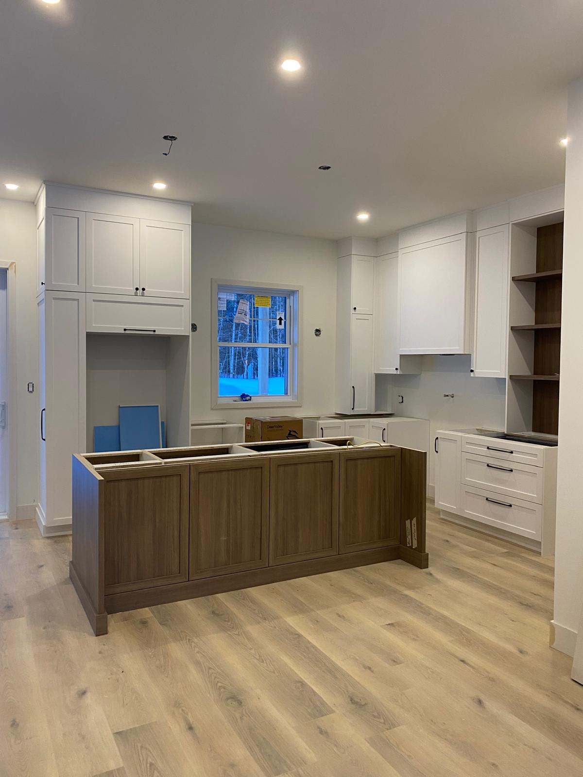 Cuisine blanche sur mesure en cours d'installation avec îlot en bois et étagères intégrées
