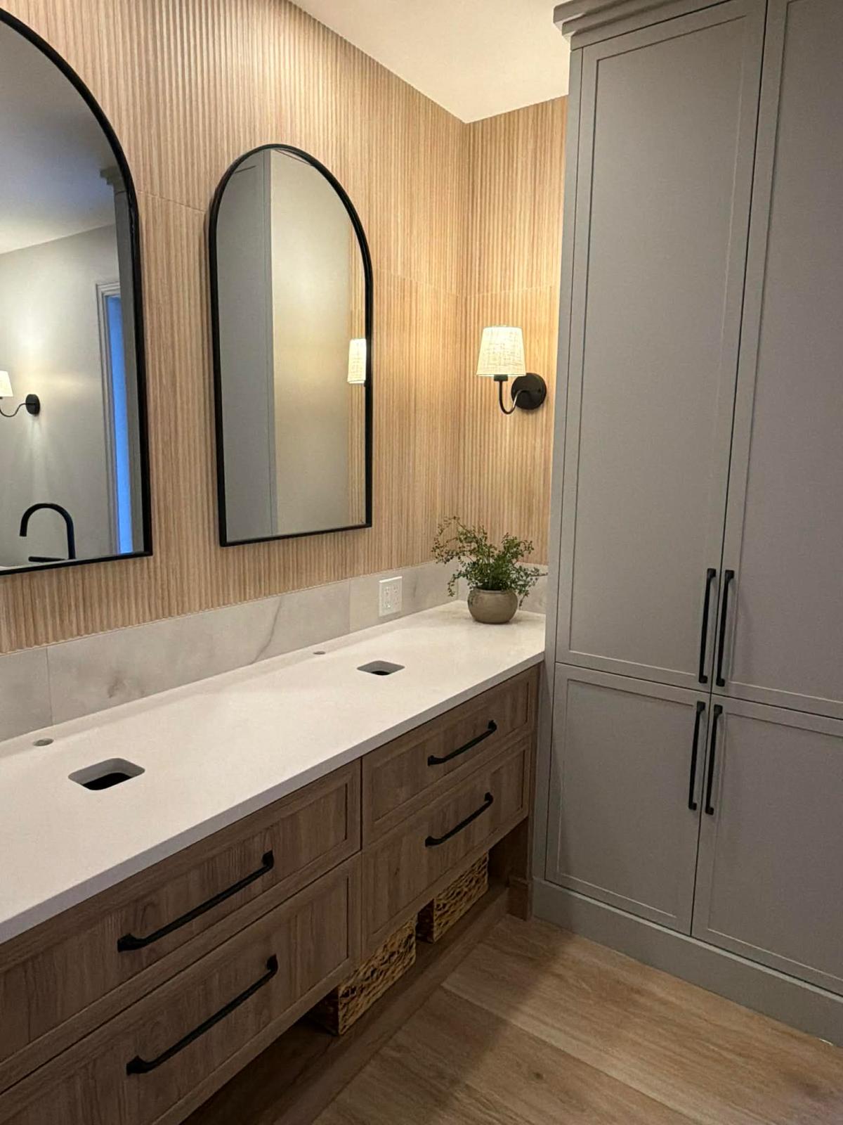 Salle de bain sur mesure avec vanité double en bois, miroirs arqués noirs et colonne de rangement grise
